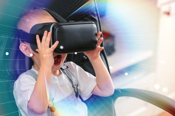 Child using new Virtual Reality, VR cardboard glasses. happy little boy with virtual reality headset sitting on sofa. Toned photo