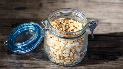 Fried peanuts in a jar on wood background.