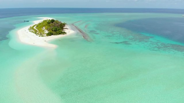 Aerial: Flying over idyllic atoll, scenic travel destination in Wakatobi National Park Indonesia Maldives Polynesia blue lagoon turquoise water coral reef desert island white sand beach
