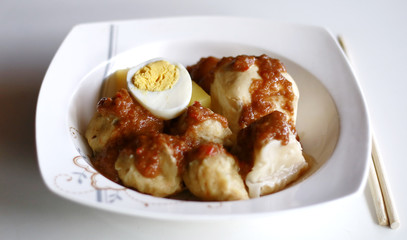 Siomay (fish cake dumplings) and peanut sauce on white background. 