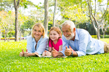 Happy Old Grandparents Having Fun With Grandchildren read a book In Park