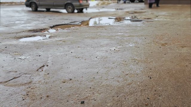 Puddles on broken road and asphalt with pits. ars driving on bad road surface