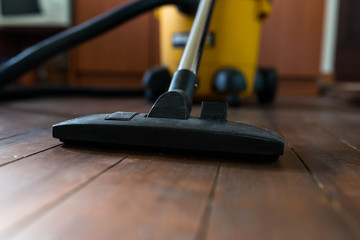 Industrial vacuum cleaner on dusty wooden floor close up, shallow depth of field, copy space.