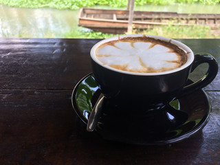 Hot cappuccino coffee in a black cup in a natural coffee cafe 
