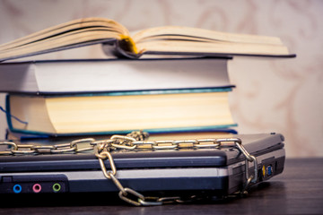 An open book is lying on a laptop that is linked by a chain. Books instead of computers. Love to read_