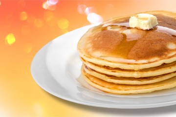 Stack of tasty pancakes with butter on a white plate