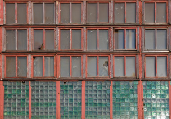 Fototapeta na wymiar Large long windows in a large old abandoned industrial factory building, closeup