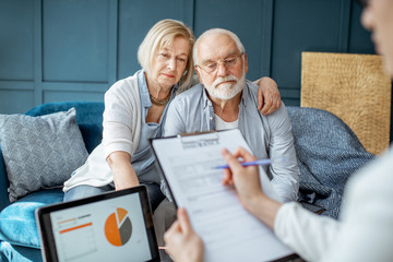 Senior couple with sad emotions during the meeting with financial consultant, signing some...