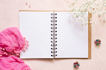 Romantic stories: open notepad, pink scarf, white flowers and multi-colored earrings