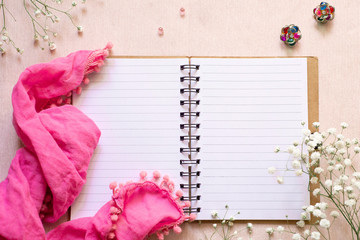 Romantic stories in a women's diary: an open notebook, a pink scarf, white flowers and multi-colored earrings