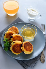 Cottage cheese pancakes with blueberry, honey, jam and coffee. Ukrainian syrniki, cottage cheese fritters or pancakes on gray wooden background. Healthy eating concept. Selective focus