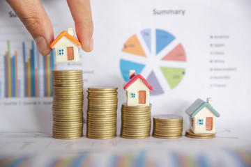 Human hand putting house model on coins stack,  planning savings money of coins to buy a home...