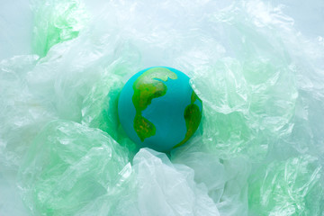 top view of a small model of the  Earth planet among plastic bags, environment, global pollution ...