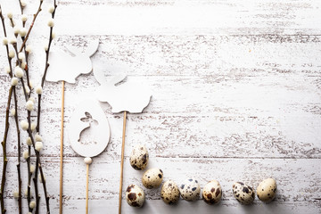 Easter natural quail eggs, willow branches and easter bunny on a wooden background