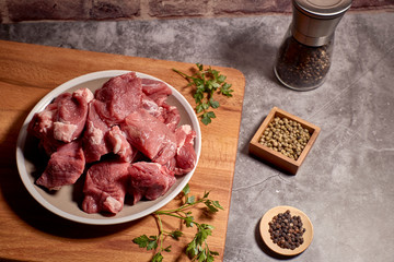 pieces of red veal meat on a wooden board and next to different spices