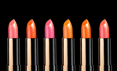 Shimmering glitter multicolored sticks of lipstick colored background isolated on black