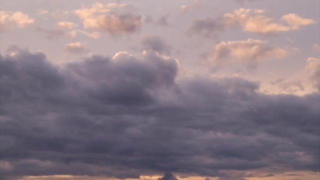 4k time lapse of red, orange and pink backlit clouds rolling by overhead at sunset.