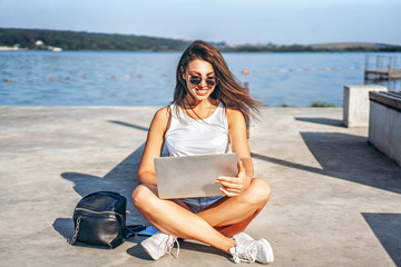 Fototapeta premium Pretty young girl using laptop outdoor in the city park.