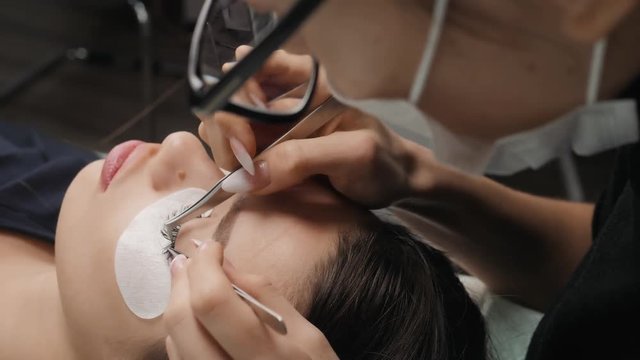 Eyelash Extension Procedure. Woman Eye with Long Eyelashes. Lashes, close up, macro treatment beauty salon