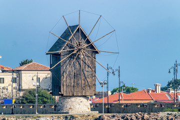 Fototapeta na wymiar The wooden windmill on the isthmus Nessebar ancient city, one of the major seaside resorts on the Bulgarian Black Sea Coast. Nesebar or Nesebr is a UNESCO World Heritage Site. The windmill in Nessebar