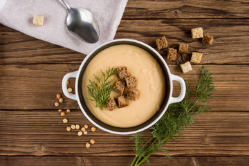 pea soup with croutons and greens on a wooden background
