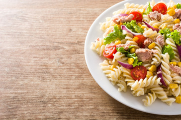 Pasta salad with vegetables and tuna on wooden table. Copyspace