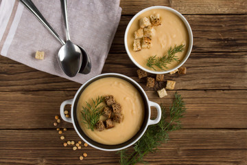 pea soup with croutons and greens on a wooden background