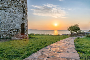 Sun rising from the sea on the Black Sea Coast. Alley at sunrise in Nessebar ancient city with ancient Tower at the left. Nesebar, Nesebr is a UNESCO World Heritage Site. Sunrise in Nessebar, Bulgaria