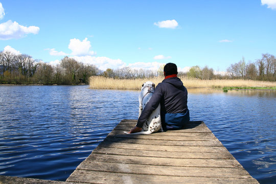 un homme et son chien assis sur un ponton