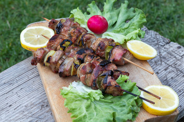 Grilled Pork Kebab with lettuce leaves, radish and lemon over wooden background, Eastern cuisine