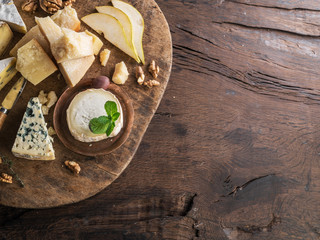 Cheese platter with organic cheeses, fruits, nuts on wooden table. Top view.