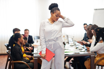 Face of handsome african american business woman, holding tablet on the background of business peoples multiracial team meeting, sitting in office table.