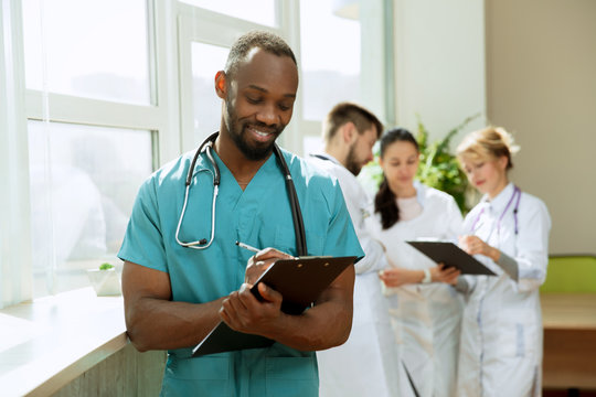 Healthcare People Group. Professional African American Male Doctor Posing At Hospital Office Or Clinic. Medical Technology Research Institute And Doctor Staff Service Concept. Happy Smiling Models.