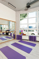 Fototapeta na wymiar Empty space in fitness center, white brick walls, natural wooden floor and big windows, modern loft studio, yoga mats, comfortable open area for sport and exercises
