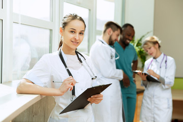 Healthcare people group. Professional female doctor posing at hospital office or clinic. Medical technology research institute and doctor staff service concept. Happy smiling models.