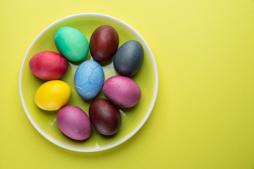 Colorful Easter eggs as an attribute of Easter celebration on the yellow plate.