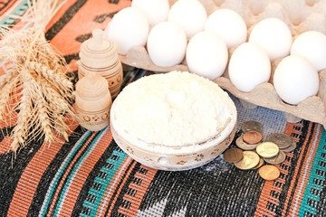 eggs, wheat, coins, wooden dishes with flour. Ingredients for making bread. Buying or selling wheat.