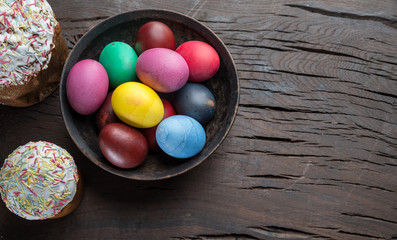 Colorful Easter eggs and Easter bread attributes of Easter celebration. Wooden background.