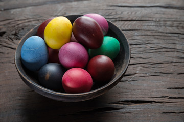 Colorful Easter eggs in bowl on wooden table. Attribute of Easter celebration.