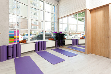 Empty space in fitness center, white brick walls, natural wooden floor and big windows, modern loft studio, yoga mats, comfortable open area for sport and exercises
