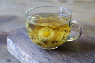 cup of chamomile tea on rustic wooden background