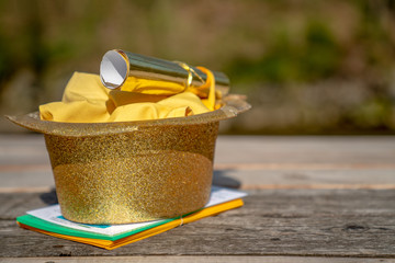 Picnic party with gold hat and party invitation on wooden picnic table.