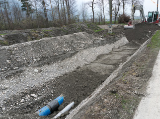 laying large industrial water pipes in an earth and dirt ditch for water supply and irrigation with...