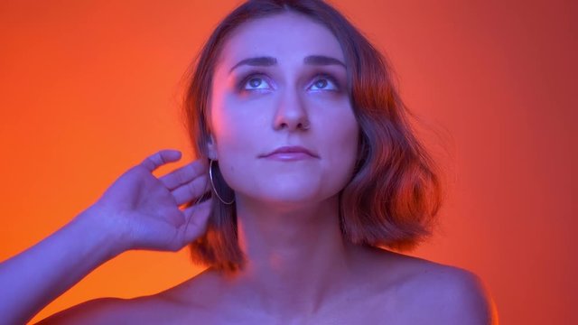 Closeup shoot of young carefree attractive caucasian female smiling happily looking at camera with neon red background