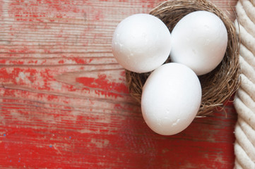 White eggs in easter nest on wood background.