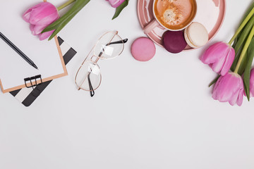 Beautiful pink tulips, cup of coffee and macarons on the white table