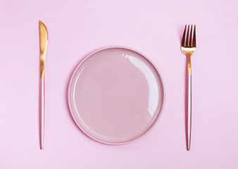 Pink plate, fork and knife isolated on pink background