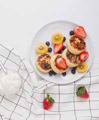 Cottage cheese pankeas with berries on the white plate