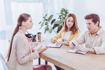 beautiful woman talking and gesturing near recruiters on job interview