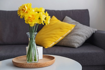 Yellow spring flowers in a vase standing in the living room on the coffe table